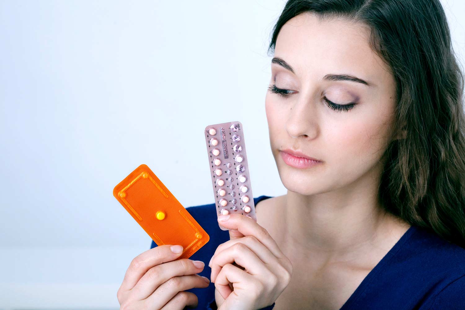 woman holds birth control and morning after pill packets