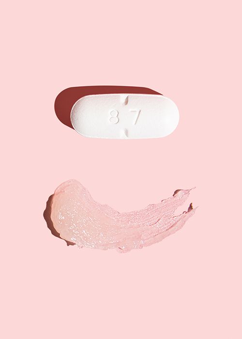 White pill and smear of topical cream to treat herpes cold sores sitting on pink background