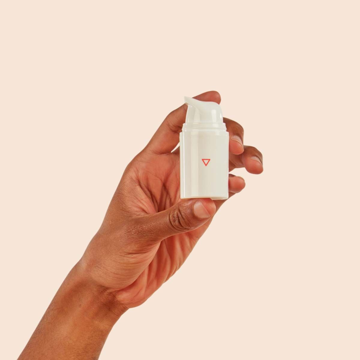 A person's hand holding a Wisp pump bottle in front of a cream background