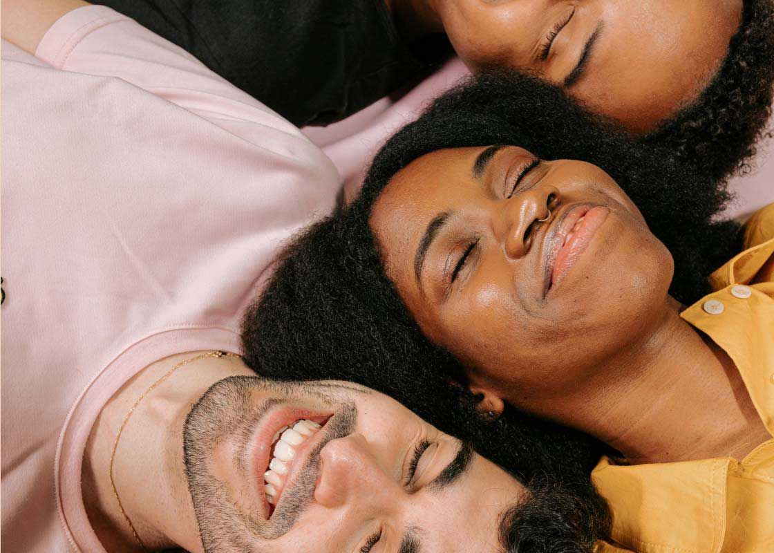 A group of smiling humans wearing colorful clothing while laying down
