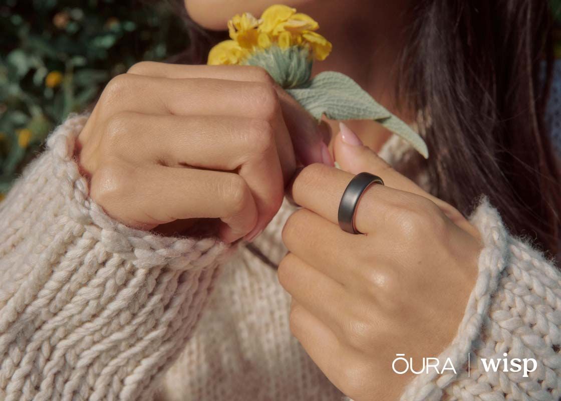 An close up a woman's hands holding yellow flowers with an Oura ring on her index finger