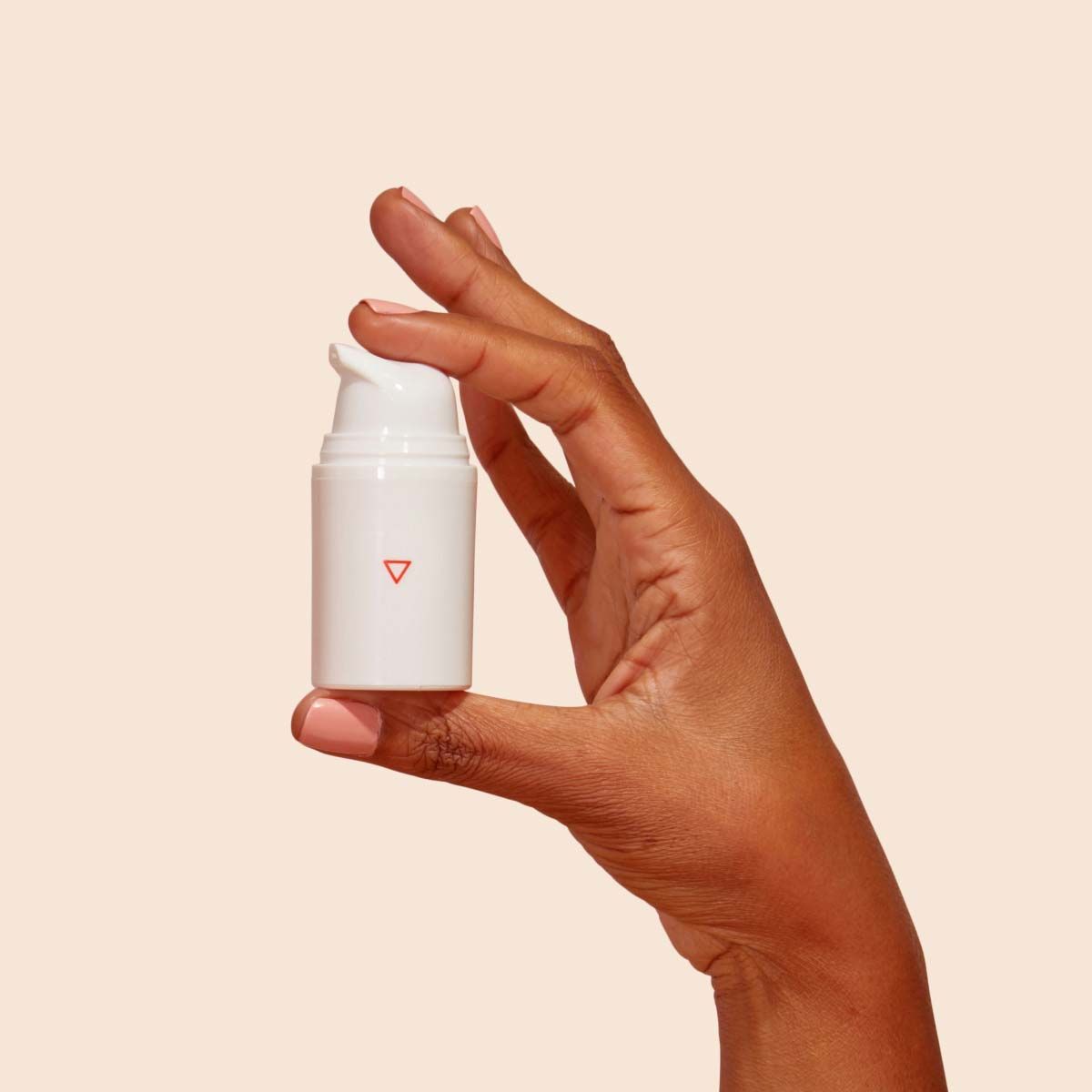 A woman's hand holding a Wisp pump bottle in front of a cream background