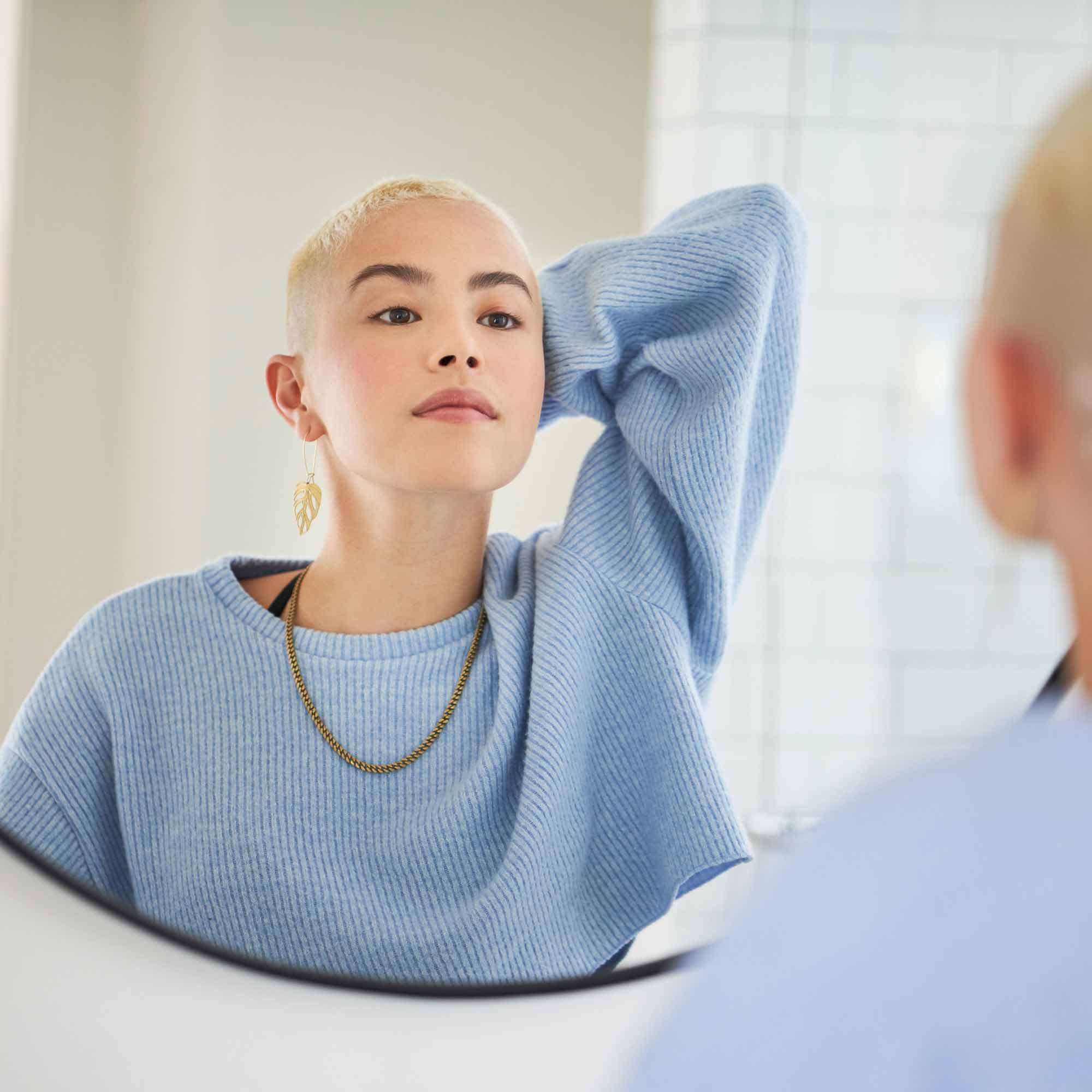 Woman looks at clear skin in the mirror