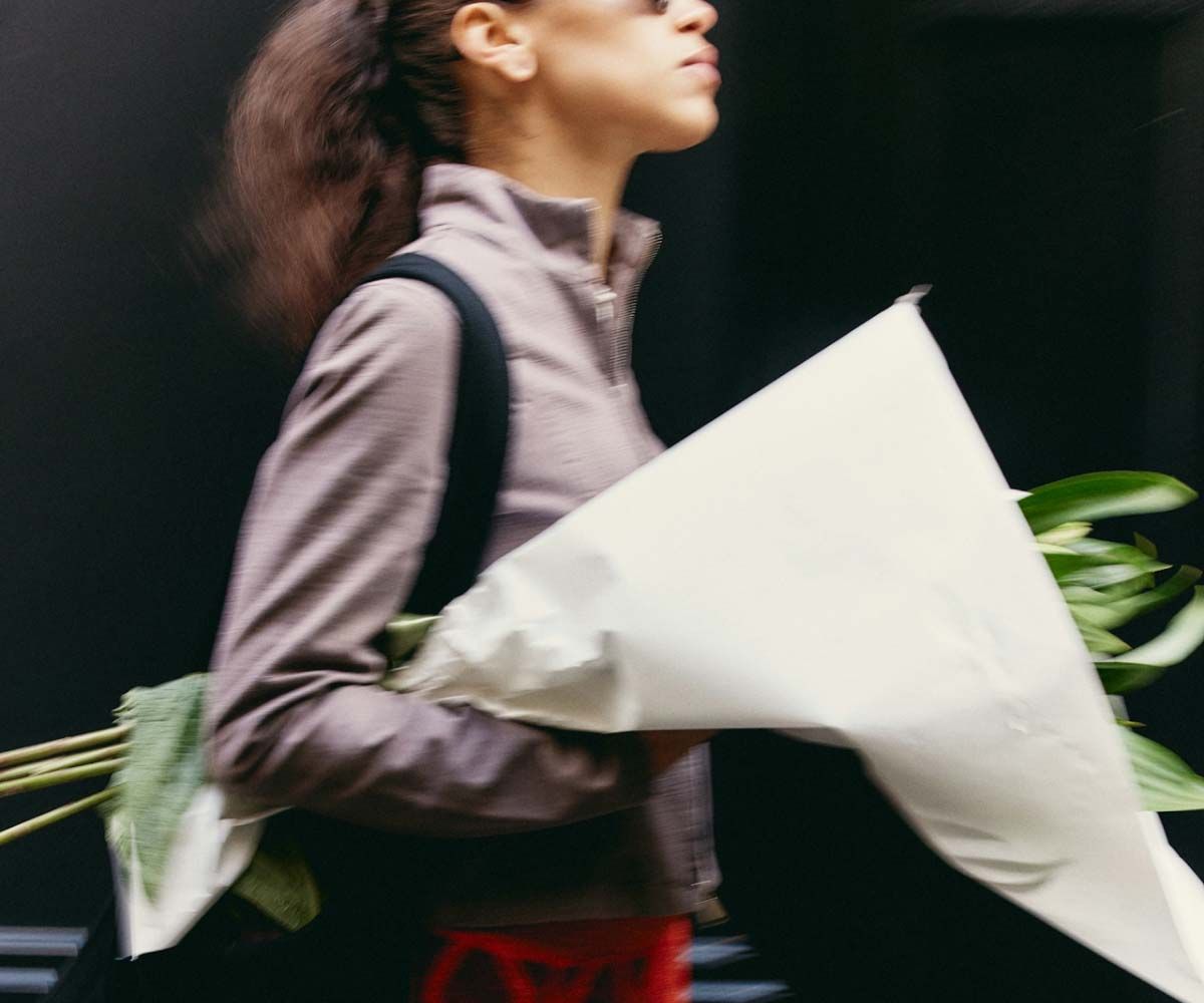 A woman wearing a gray shirt and carrying flowers outdoors
