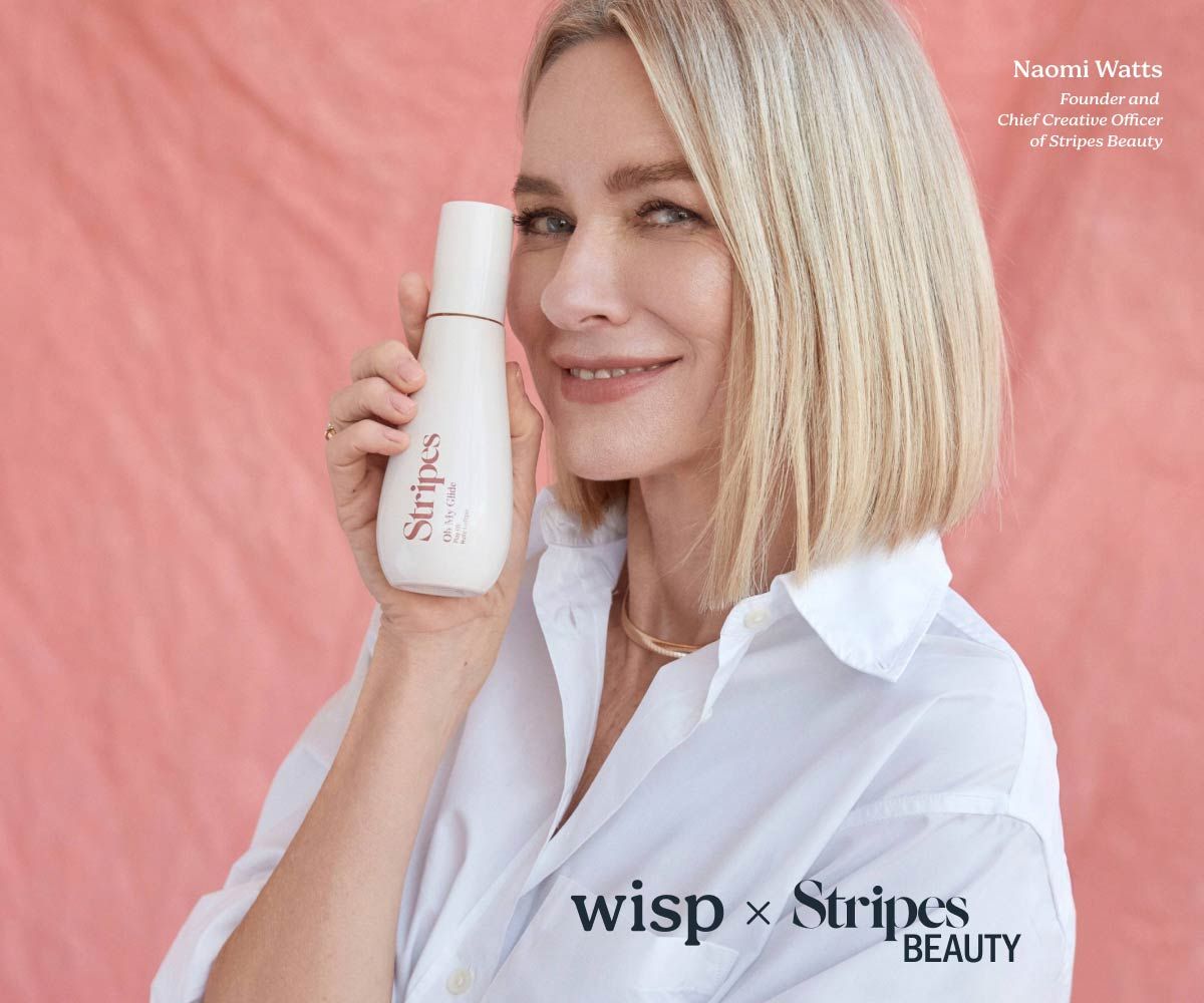 Naomi Watts wearing a white collar shirt while holding a bottle of Oh My Glide by Stripes Beauty on a pink background