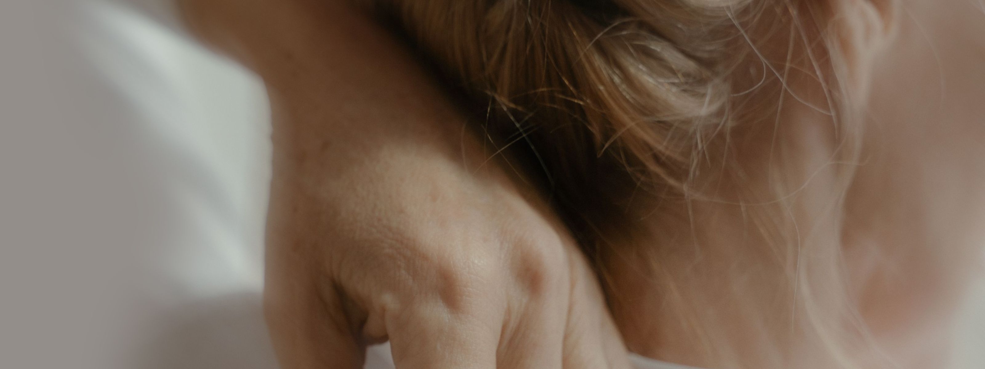 image of the back of a woman's neck with her hand touching her neck and blonde hair