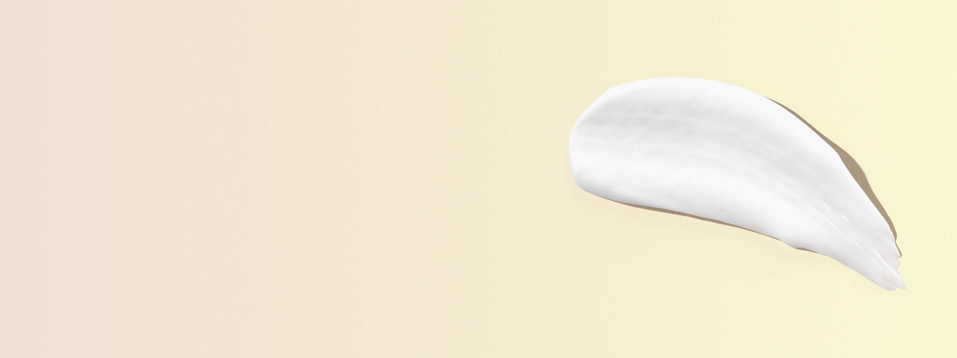 swipe of white cream in front of a yellow background