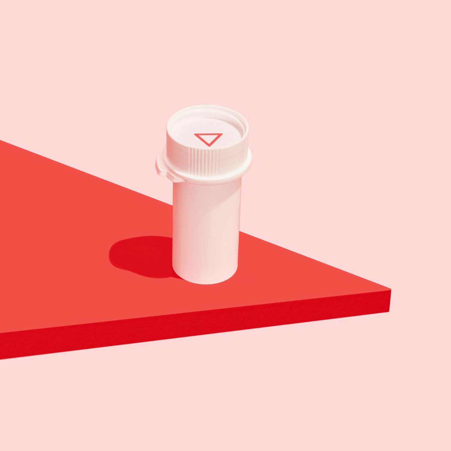 Wisp plastic pill vial on a red surface with a pink background