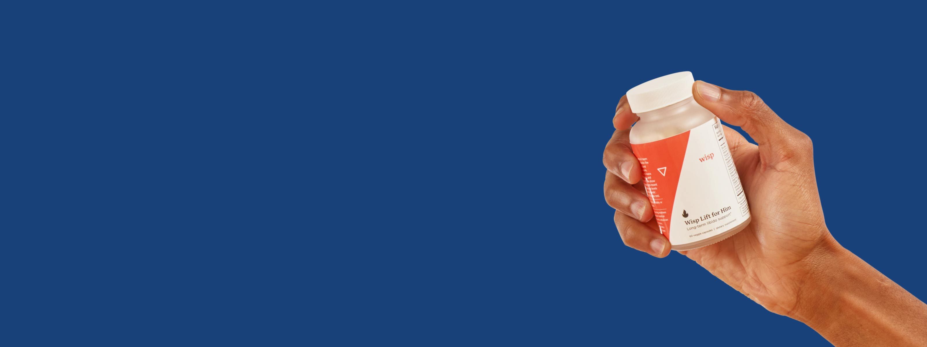 Man's hand holding Wisp Lift for Him libido supplements with a blue background