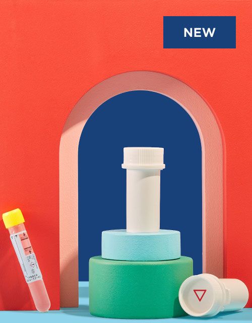 Wisp pill vials, testing tubes and a hand holding a testing pipette with colorful abstract shapes on a blue surface