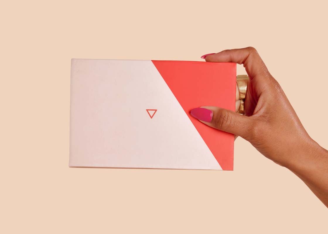 A person's hand hold a Wisp Diagnostics Kit with a cream background