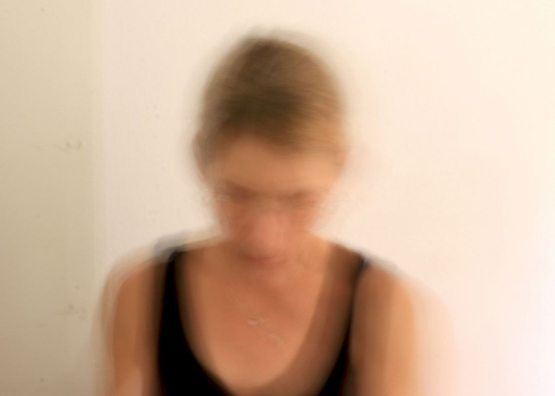 A woman wearing a black tank top and a beige background with motion blur