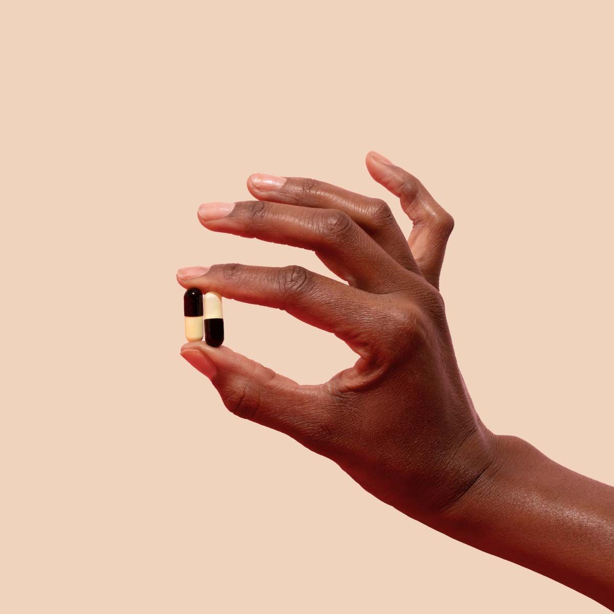 Woman's hand holding UTI antibiotics on a cream background