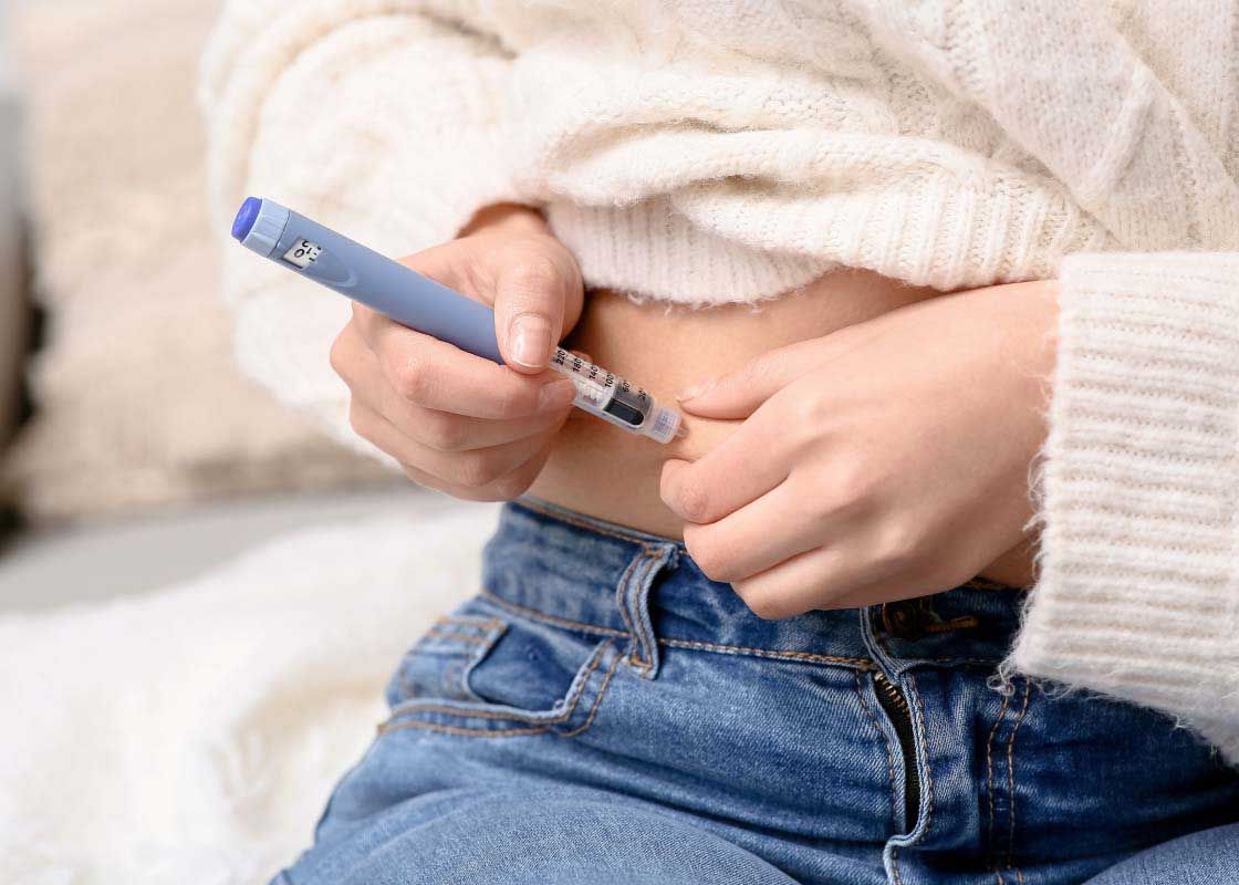 A woman giving herself an injection in her abdomen