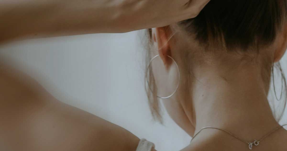 Close up of the back of someone raising their arms while wearing a white top