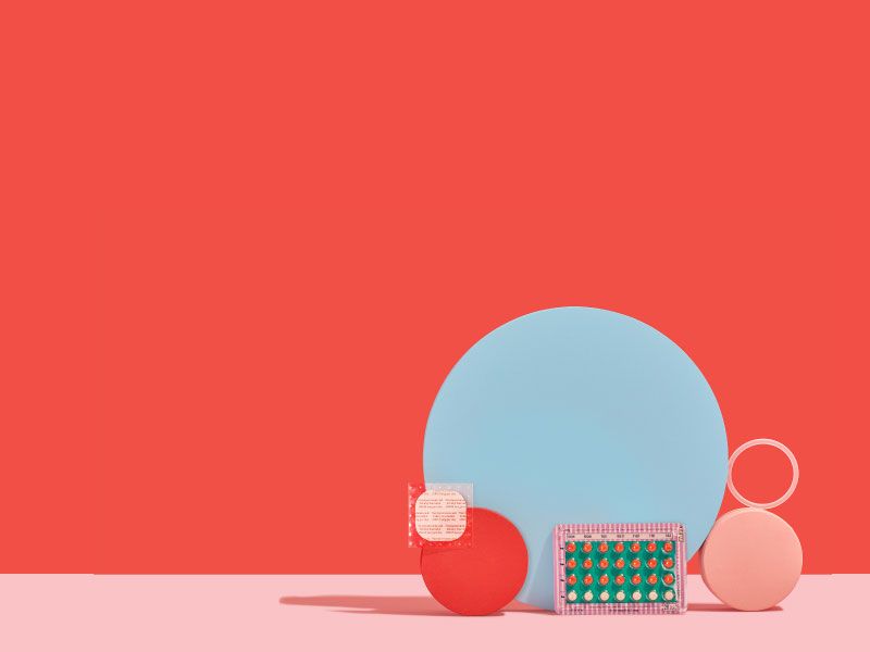 A birth control packet, NuvaRing, and the birth control patch balanced on colorful abstract shapes on a pink surface with a red background