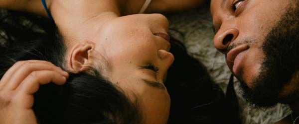 A woman and man laying next to each other with intimate expressions