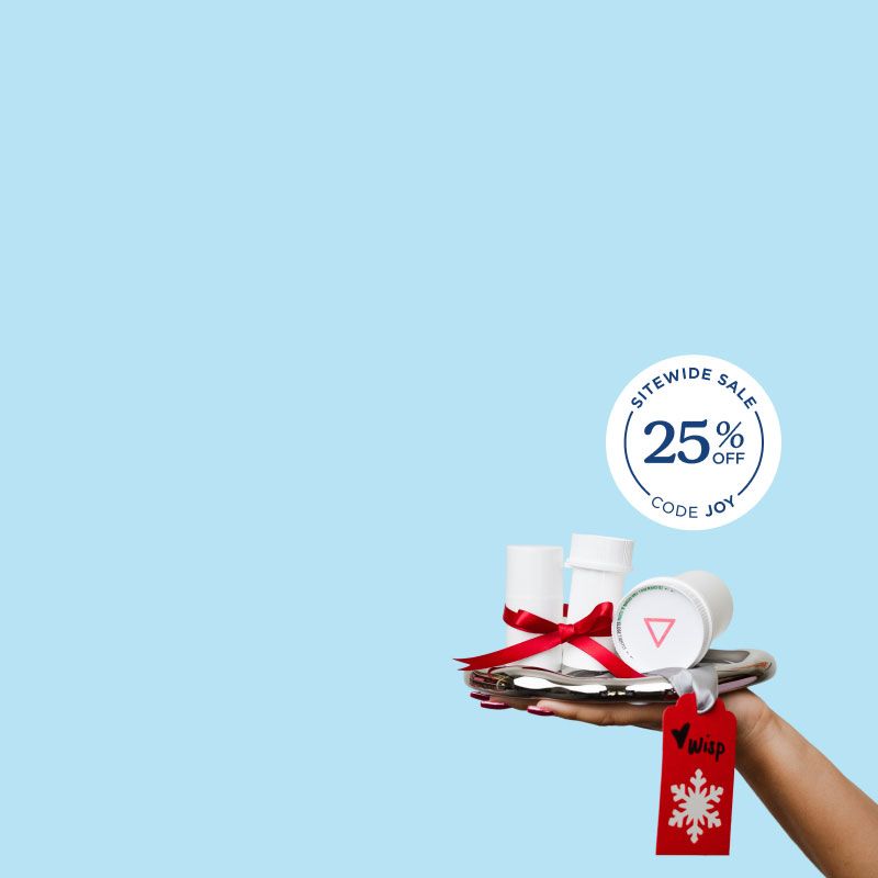 A woman's hand holding a silver tray with multiple Wisp pill vials with a red ribbon around them in front of a light blue background