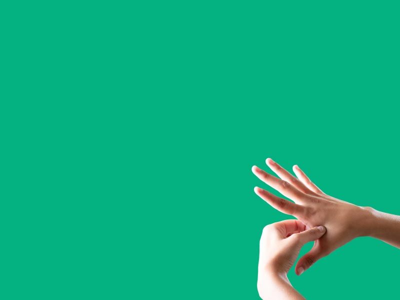 A person's hands applying pressure on a pressure point in front of a green background