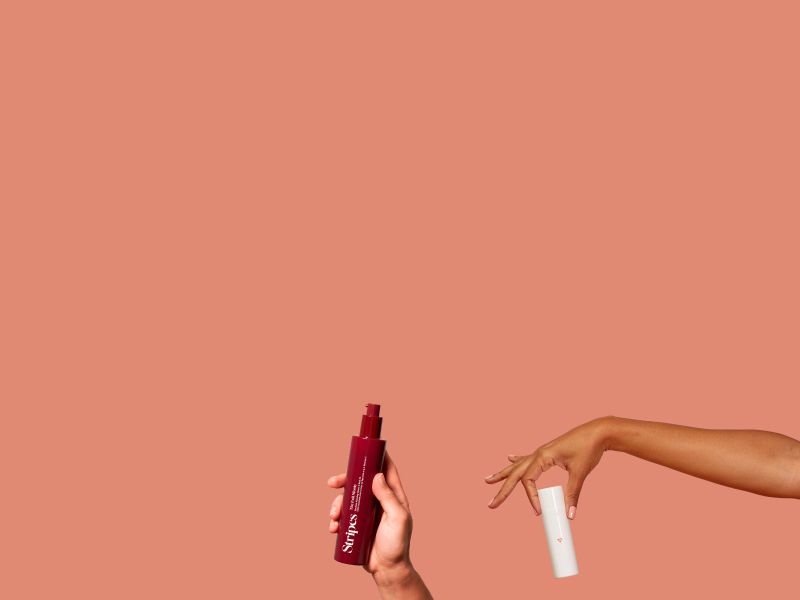 Hands holding Wisp and Stripes Beauty menopause product on a terracotta background