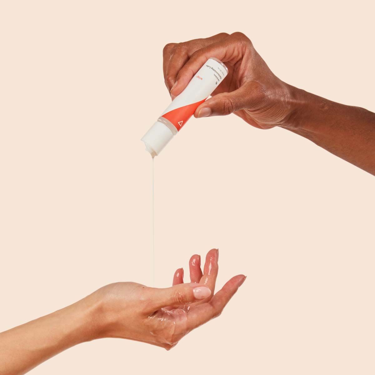 A hand squeezing Wisp Harmonizing Lube into another person's hand
