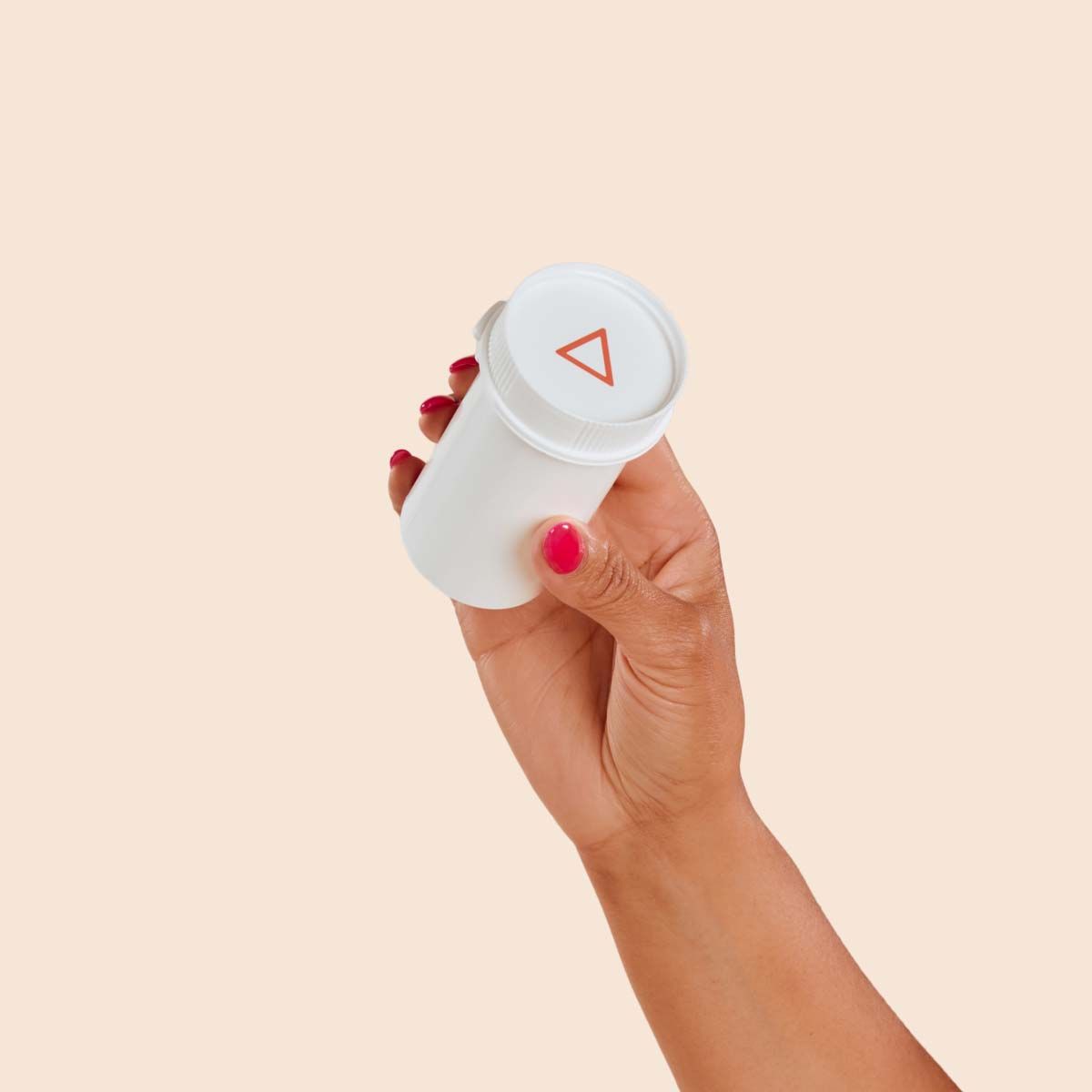 A person's hand holding A Wisp vial with a cream background
