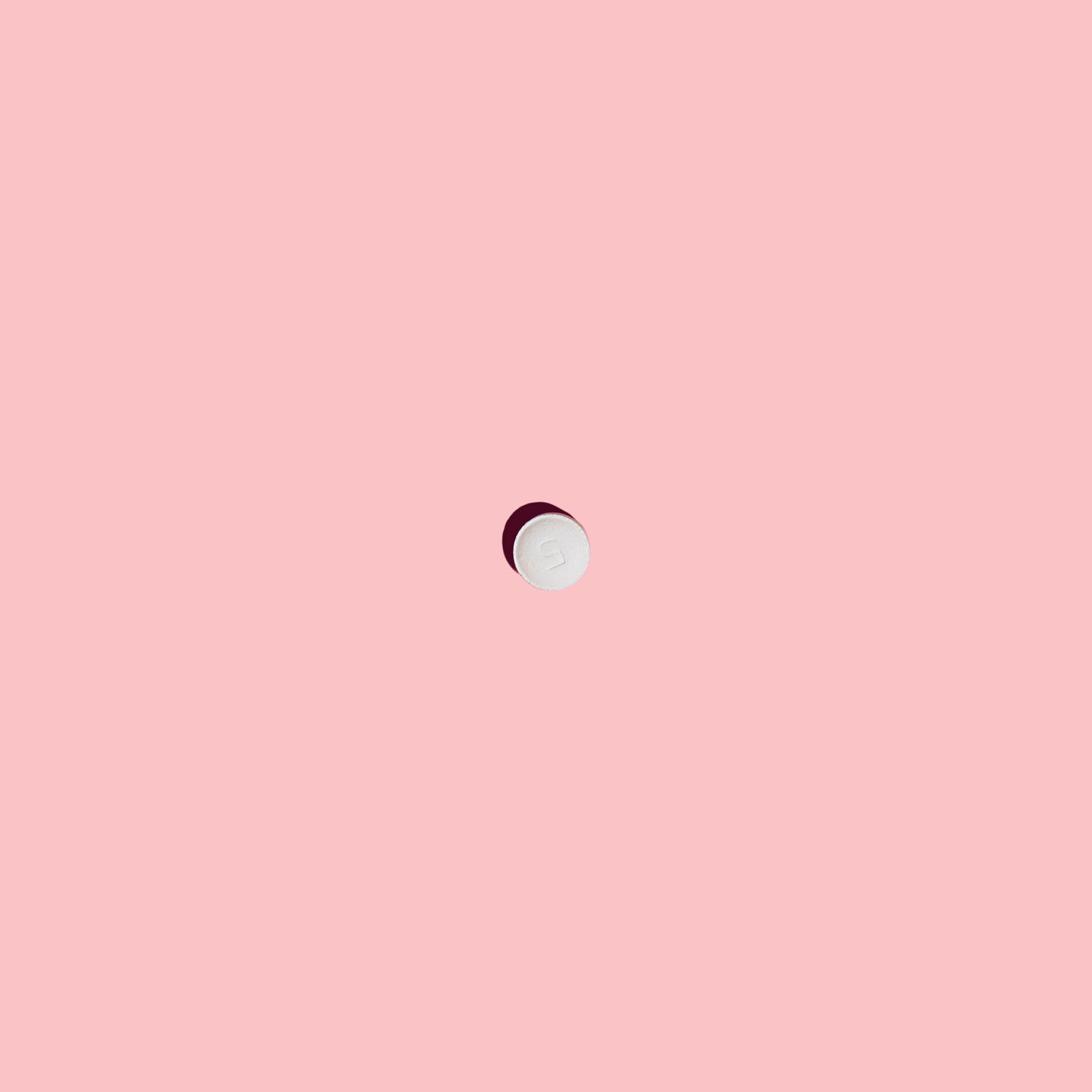 A Zofran anti-nausea pill on a pink surface