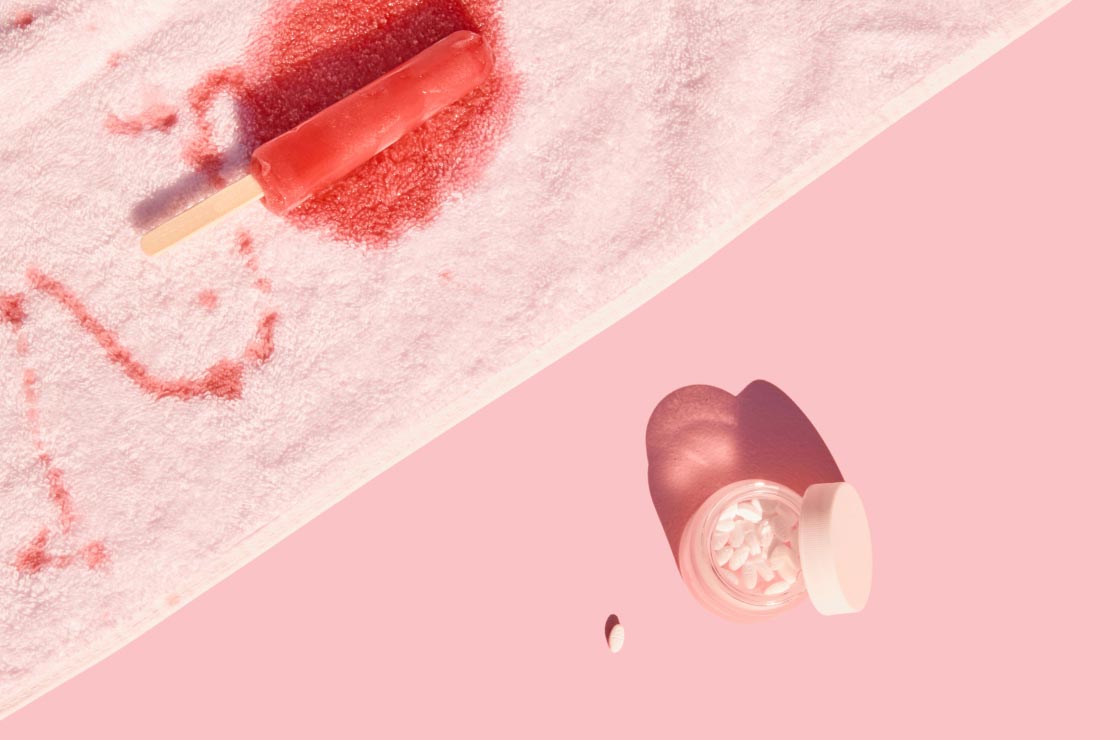 Wisp delay your period meds next to a melting popsicle on a white towel