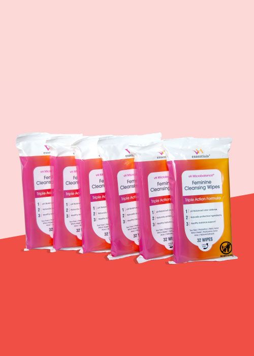 6 packs of pH vaginal wipes on a red surface with a pink background