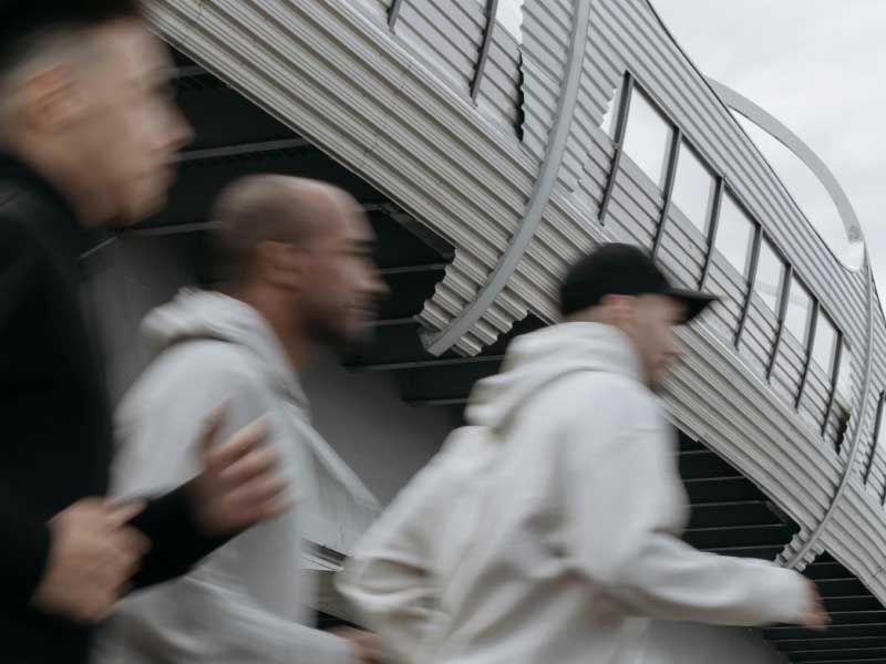 Three men in motion, jogging underneath an overpass