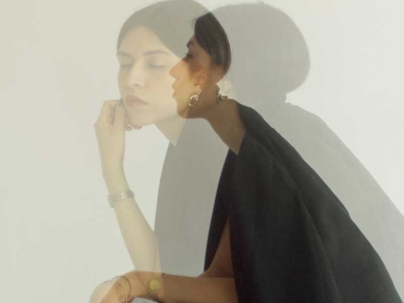 Woman in black with gold jewelry double exposure portrait