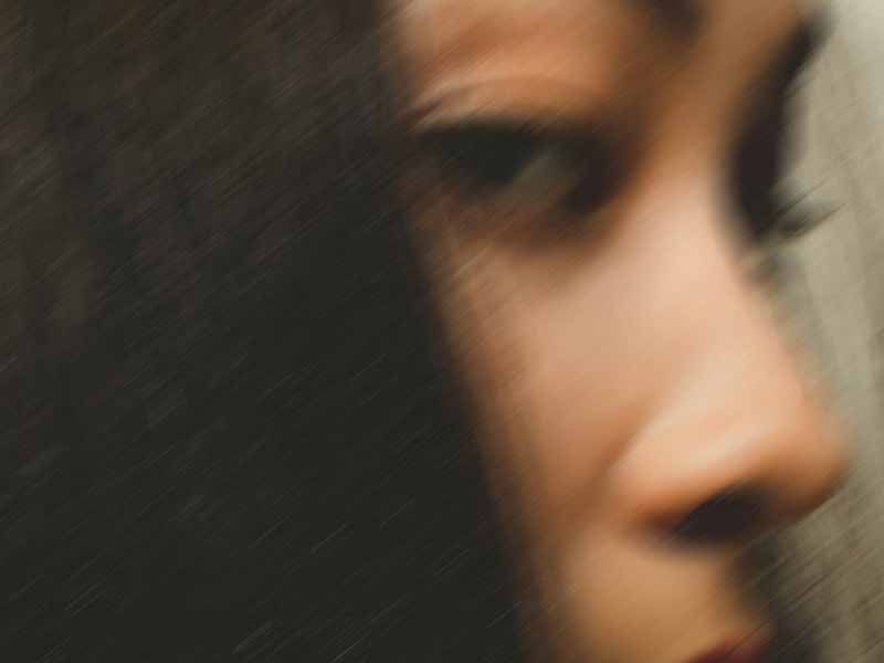 Soft-focus profile of a person's nose and lips against dark hair in low light.