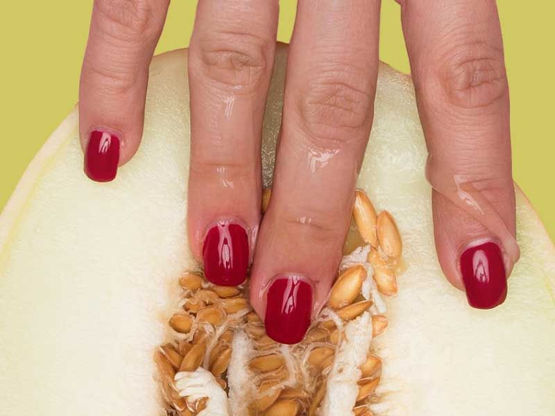 Hand touching sliced melon against green background
