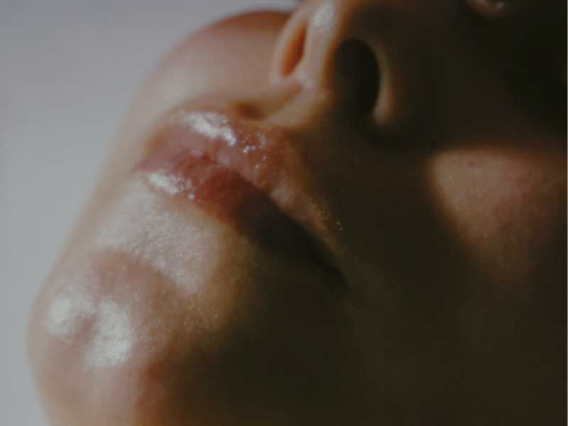 Close-up portrait of lips and nose with soft, cinematic lighting.