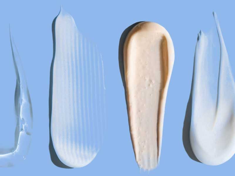 Skincare cream and gel swatches on a light blue surface