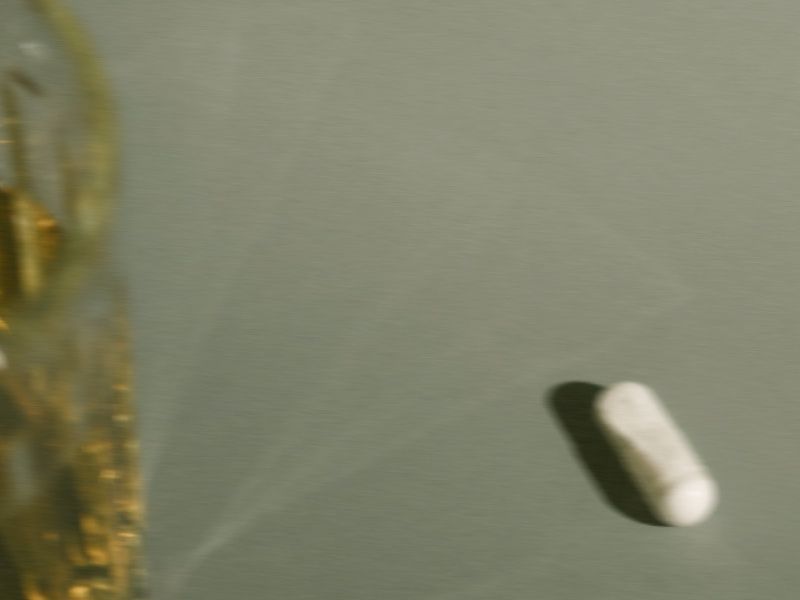 image of a white blurry pill in front of a mossy green background