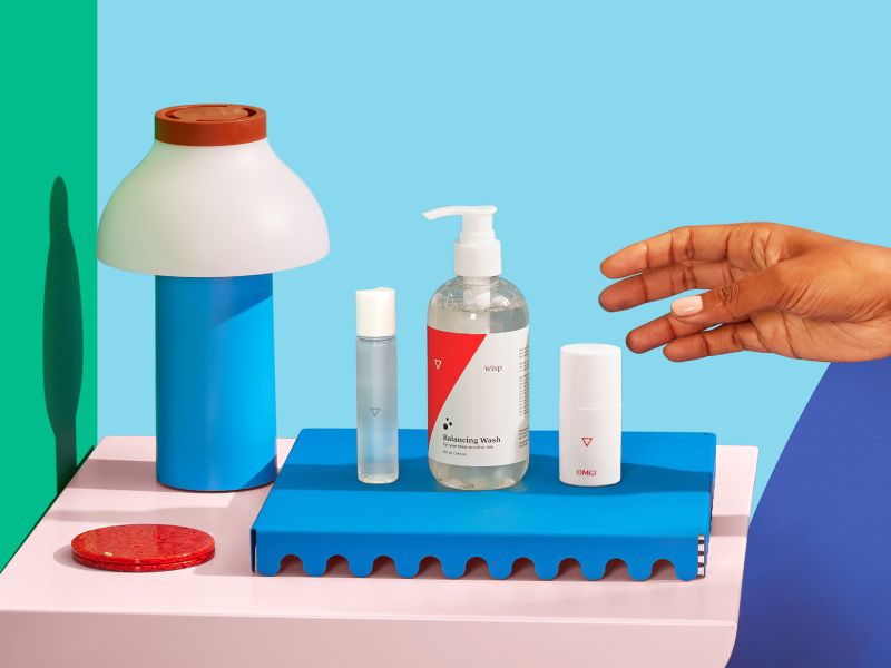 a woman's hand reaches for Wisp intimate care products on her bedside table