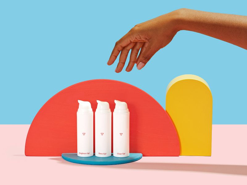 a woman's hand reaches for Wisp skincare products on a colorful geometric background
