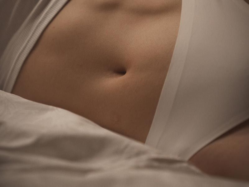 A close up of a woman's abdomen while laying in bed