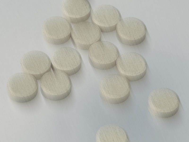 scattered white pills in front of a white background