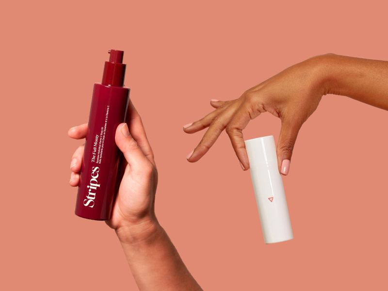 Hands holding Wisp and Stripes Beauty menopause product on a terracotta background