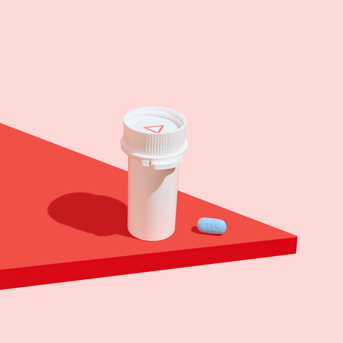 A Wisp pill vial and a blue Valacyclovir on a red surface with a pink background