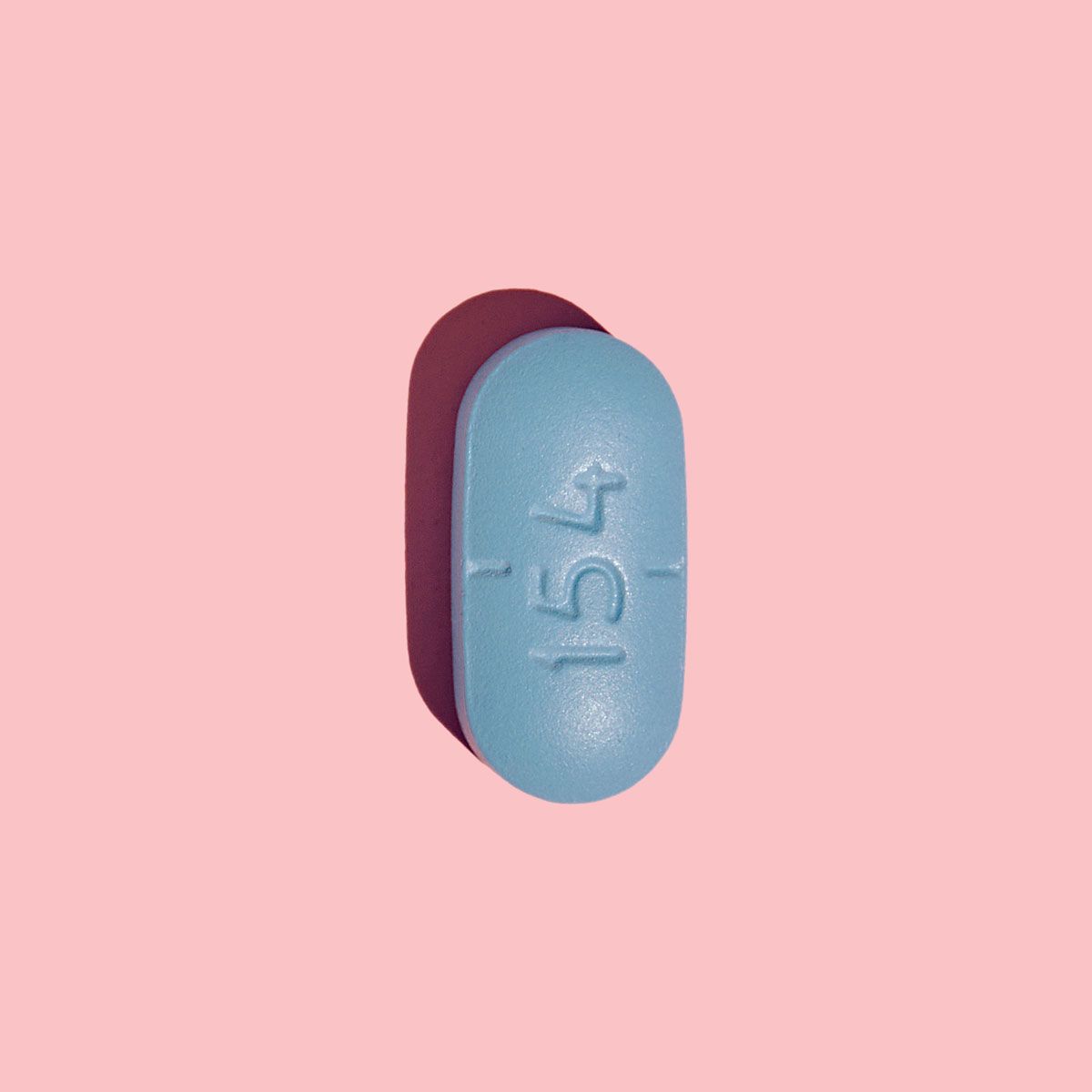 A blue Valacyclovir pill on a pink surface