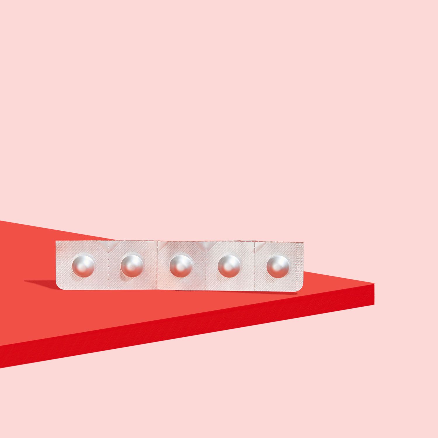 A Zofran pill packet on a red surface with a pink background