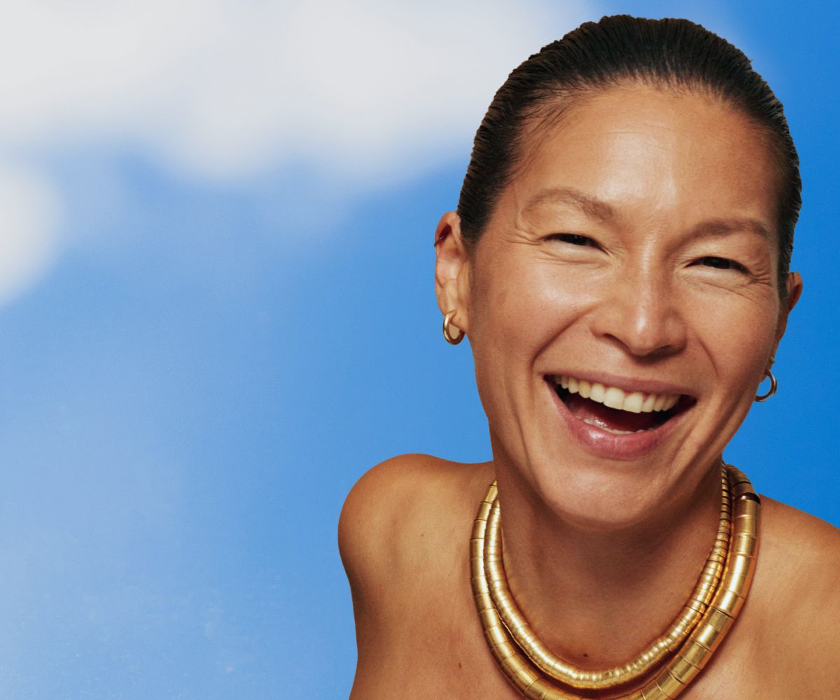 smiling woman against a sky blue backdrop with clouds