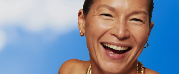smiling woman against a sky blue backdrop with clouds