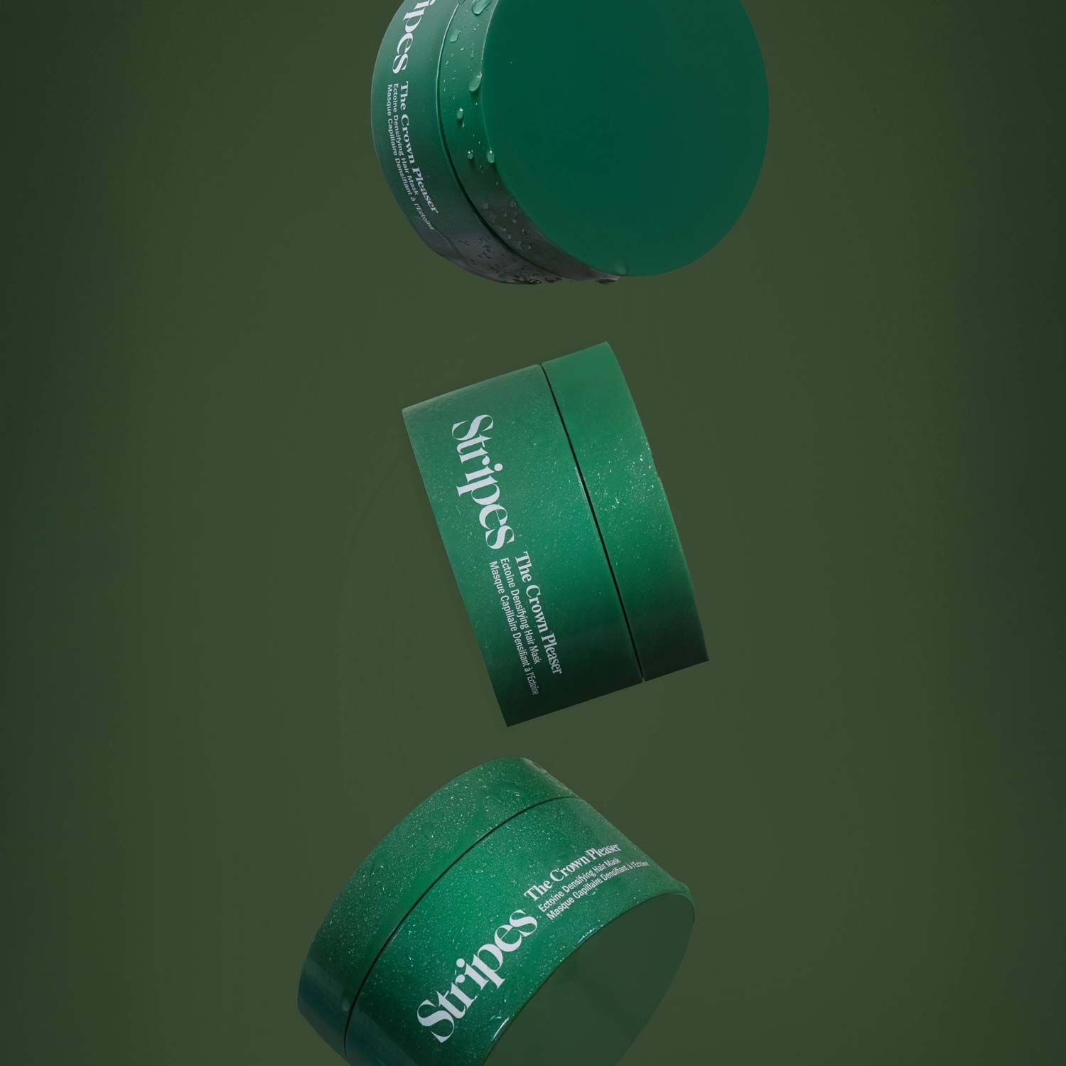 3 tubs of the Crown Pleaser by Stripes Beauty in front of a dark green background