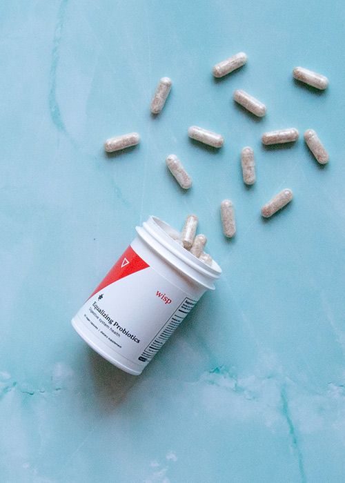 Wisp Equalizing Probiotics spilling on a marble background