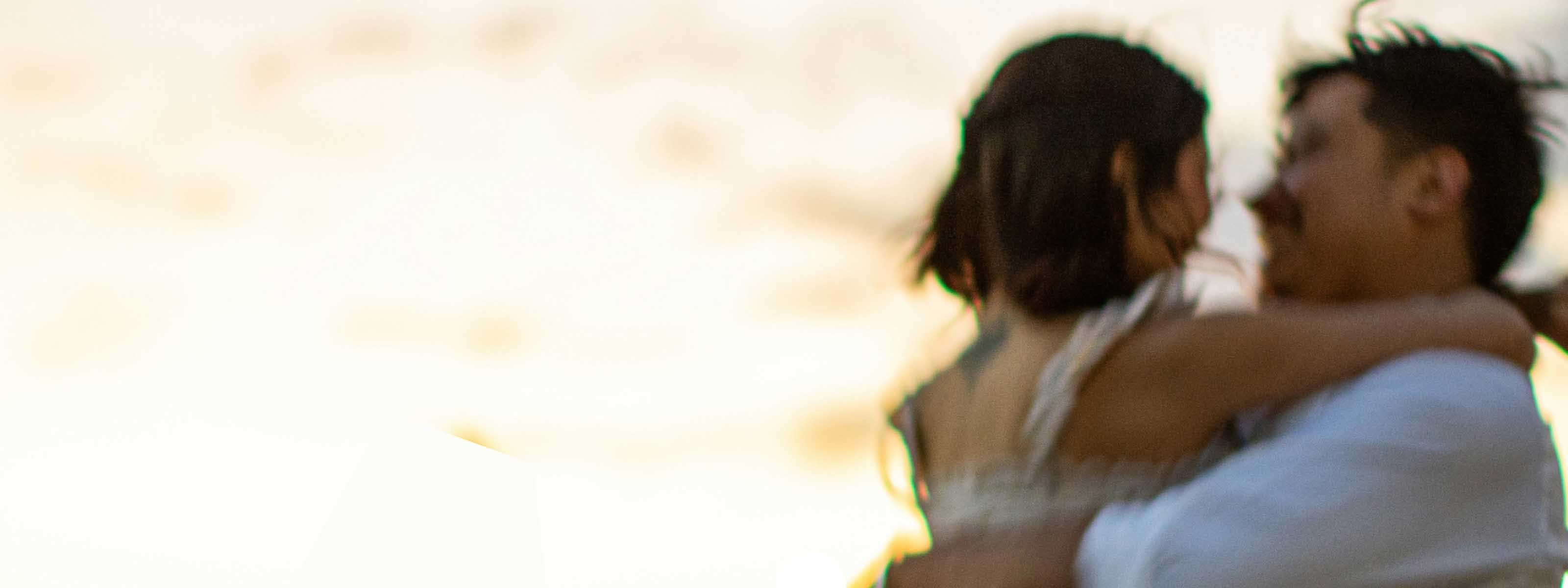 Blurred couple embracing outdoors at sunset