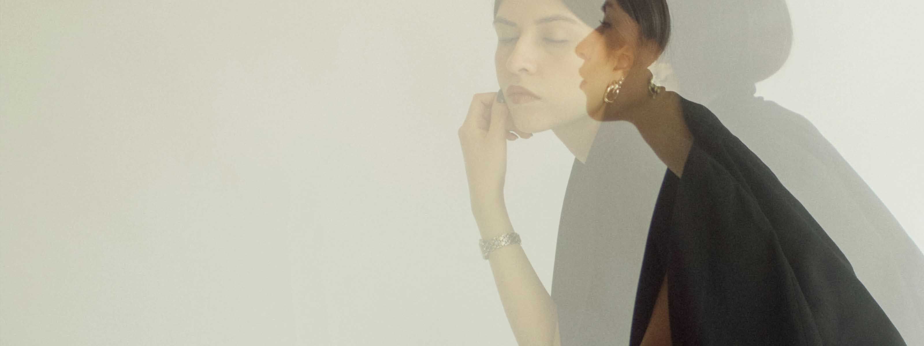 Woman in black with gold jewelry double exposure portrait